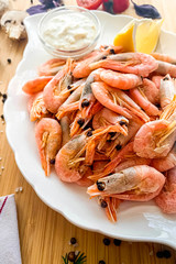Shrimp boiled with lemon sauce on a wooden table side view close-up, shrimp appetizer for beer