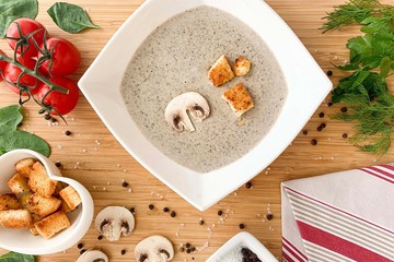 Cream-soup of mushrooms with crackers on a wooden table, view from the top