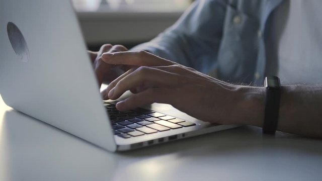 Closeup of man hands typing at laptop in the business workplace office. Spbd electonic apple watch on male hand. concept working, desktop, device. hipster guy freelancer