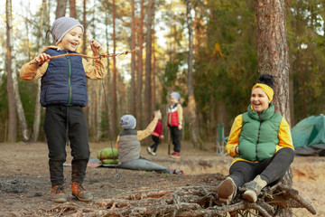 happy mother resting in the forest with happy happy children, children play in a forest glade, camping, travel, tourism, hike and people concept