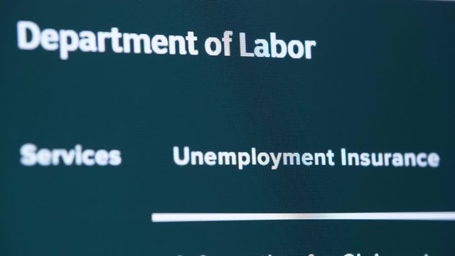 human finger selects and press hyperlink unemployment insurance on Department of Labor website section, unemployed try to get online help in crisis situation, quarantine and isolation, closeup screen 