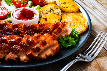 Grilled sausages and vegetables on wooden board

