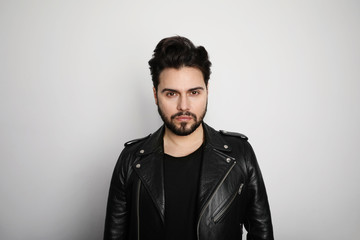 Portrait of modern young bearded hipster man in a leather stylish jacket posing over a white background.