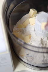 Fototapeta na wymiar Adding diced butter into food processor with flour. Making Boston Banoffee Pie.