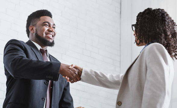African American business partners shaking hands in office, making agreement