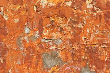 Red with orange concrete wall with cracks and scratches. Texture of scratched, old and worn wall close up.