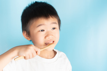 An Asian child is holding a toothbrush.