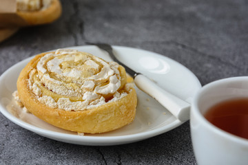 Cake with curd filling on a white ceramic plate next to a dessert fork, close up 