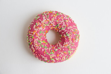 Colourful glazed doughnut with different sprinkles lies on grey background. Selective focus. Junk Food Theme.