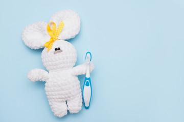 toy bunny with a toothbrush on blue background . copy space