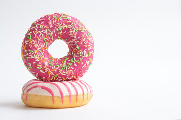 Two colourful donuts lies on white background. Horizontal photography. Copy space for your text. Theme of delivery from Fast Food Restaurant