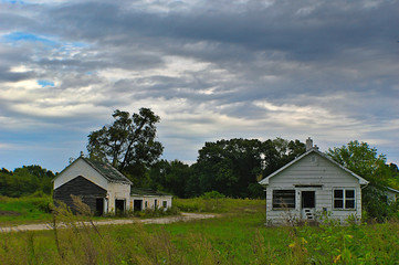 Obraz premium Abandoned farm house and barn in rural midwest as the sun begins to set