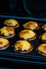 Pasteis de Nata or Belem Tart. Portuguese Custard made with Egg, Cinnamon, Sugar and Flour in Muffin Tray / Cupcake Mol in Oven.