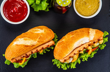 Hot dogs, French fries and vegetables on black stone board
