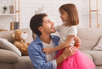 Small pretty girl putting crown on her dad