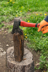 Hands hold an ax and chop wood on a stump