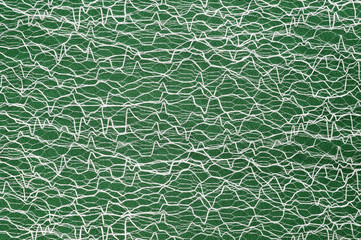 Guipure lying on a colored cloth, photographed close-up. Background for the texture of outerwear and fashion.