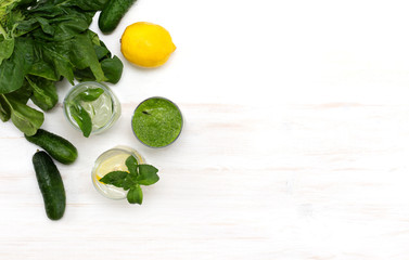 Blended green spinach smoothie and detox water with cucumber and lemon for diet healthy eating and weight loss on white background. Summer veggie healthy drink with ingredients. Top view, copy space