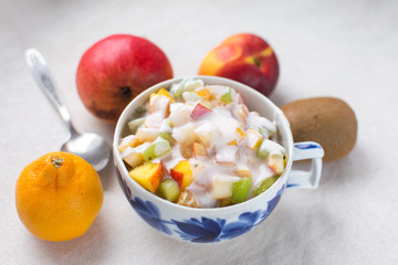 fruit salad serving in a Cup with fresh milk yogurt and a metal spoon isolate on a white background kiwi nectarine pear Mandarin