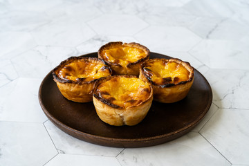 Pasteis de Nata or Belem Tart. Portuguese Custard made with Egg, Cinnamon, Sugar and Flour on Wooden Plate.