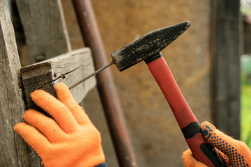 Hand in orange gloves hammer a nail