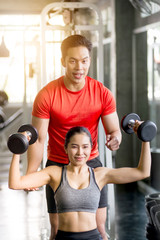 Fototapeta premium The trainer is teaching exercise to charming women Dumbbell Lifting Course for Strengthens Muscles, Online Live Streaming, Exercise Tutorials, Exercise Concept at Home.