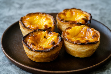 Pasteis de Nata or Belem Tart. Portuguese Custard made with Egg, Cinnamon, Sugar and Flour on Wooden Plate.