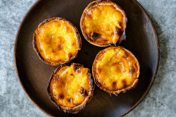 Pasteis de Nata or Belem Tart. Portuguese Custard made with Egg, Cinnamon, Sugar and Flour on Wooden Plate.