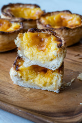 Pasteis de Nata or Belem Tart. Portuguese Custard made with Egg, Cinnamon, Sugar and Flour on Wooden Plate.