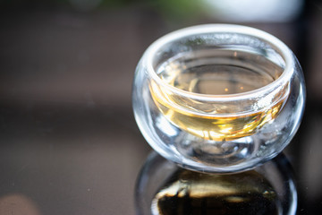The syrup in clear cup on mirror surface with reflection.