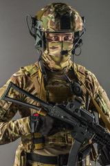 Fototapeta premium Soldier holding assault rifle. Uniform conforms to special services of the Russian Federation. Shot in studio. Isolated with clipping path on grey background