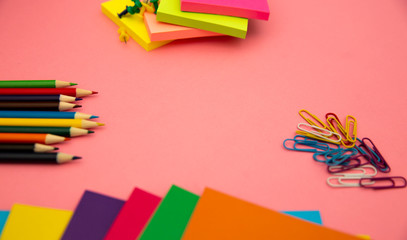 Fototapeta premium Pencils, multicolored papers and paper clips on a pink background