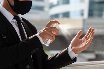 Hands of businessman spray alcohol on his hands to clean up after touch everything