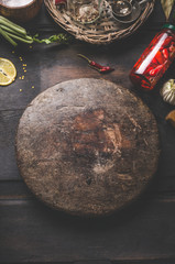 Food background with preserved chili. Home cooking. Vintage wooden round cutting board on rustic table. Ingredients for tasty home cooking. Seasonings, lemon. Top view
