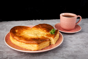 A heart-shaped casserole and a Cup of hot tea on concrete.