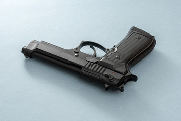 Black pistol gun isolated on the blue background.