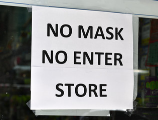 Warning sign to customers that a face mask is required to enter retail store due to COVID-19 coronavirus pandemic