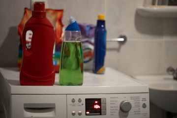 Washing machine in the bathroom. Plastic detergent box and sachets on the washing machine. Closeup.