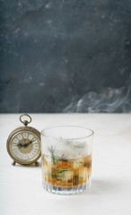 Misted glass of whiskey on the rocks in a smoke. Whiskey o'clock