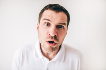 Young man isolated over white background. Portrait of wondered and amazed guy looking straight close on camera. Emotional man.