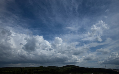 Wide angle photo of cloudy blue sky. Mountains appear under the photo. Width angle.