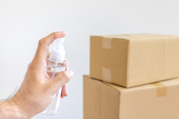 開く前のダンボール箱を除菌スプレーで消毒する男性