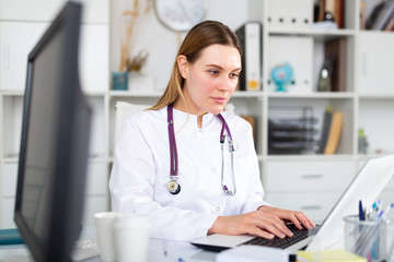 Female doctor working on laptop in clinic office