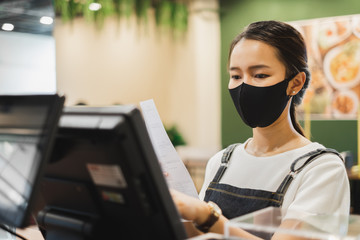 Asian staff restaurant waitress wear protective face mask working in the restaurant with social...