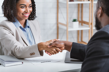 African American hiring manager shaking hand of vacancy candidate during employment interview in...