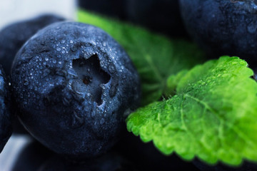 macrophotography of blueberries with mint leaves with water drops on the surface. blackberries with green leaves with carved edges