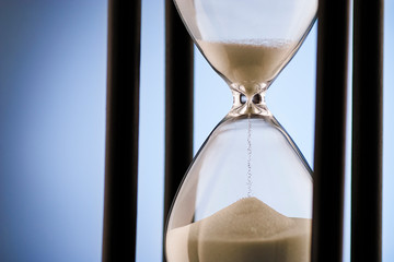 Hourglass measuring passing time over blue