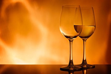Two glasses with white wine on an orange background