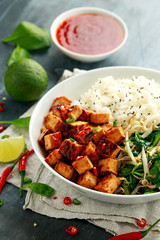 Fried tofu in sweet chilli glaze served with rice, steamed spinach and beansprouts in white bowl. Vegetable healthy food