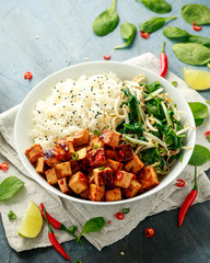 Fried tofu in sweet chilli glaze served with rice, steamed spinach and beansprouts in white bowl. Vegetable healthy food